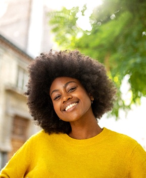 A young female wearing a yellow sweater shows off her whiter, brighter smile after completing at-home teeth whitening in Phoenix