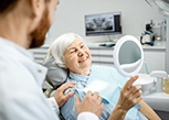 An older woman admiring her smile after a dental checkup