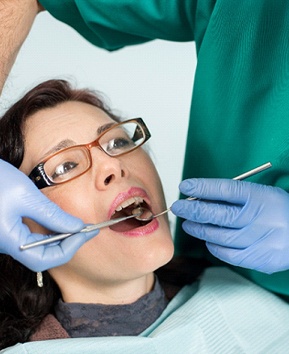 A female patient having her mouth examined by a male dentist