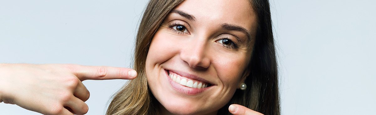 Woman pointing to her smile